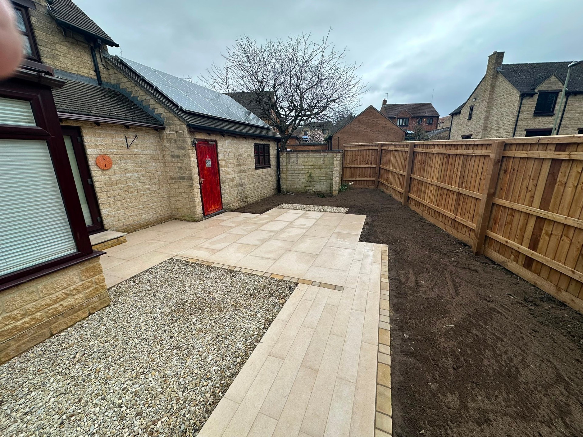 Modern sandstone patio with gravel borders and new timber closeboard fencing in a garden build.