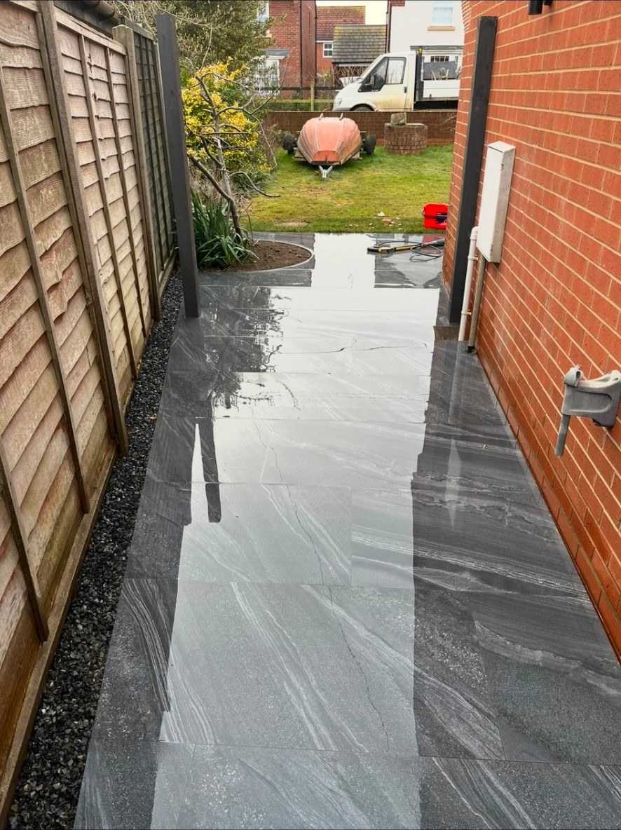 Newly installed grey porcelain tile path and patio area in a domestic side access.