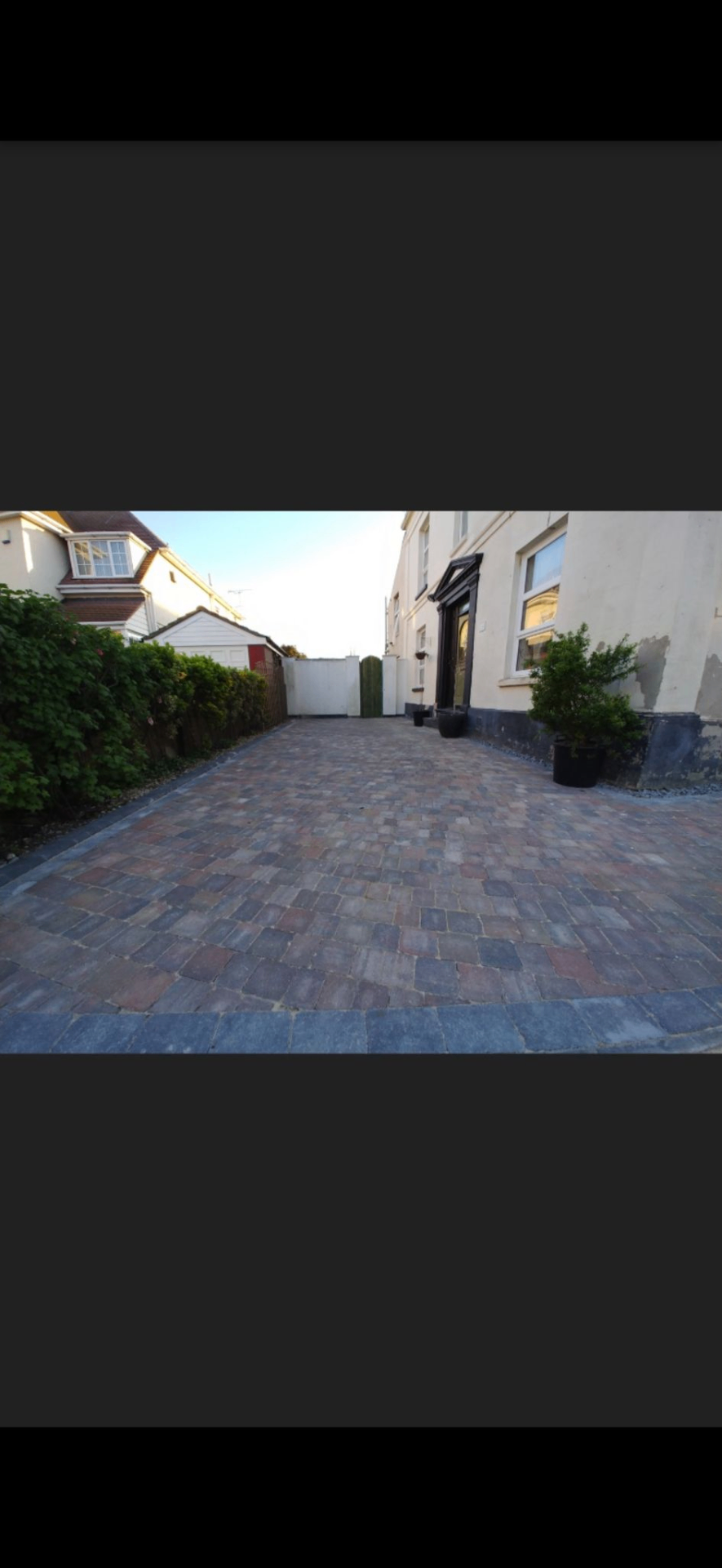 Multi-tonal block paving driveway leading to a Victorian period property with hedging and potted shrubs.