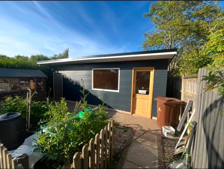 Modern dark grey garden room with timber door and resin garden path
