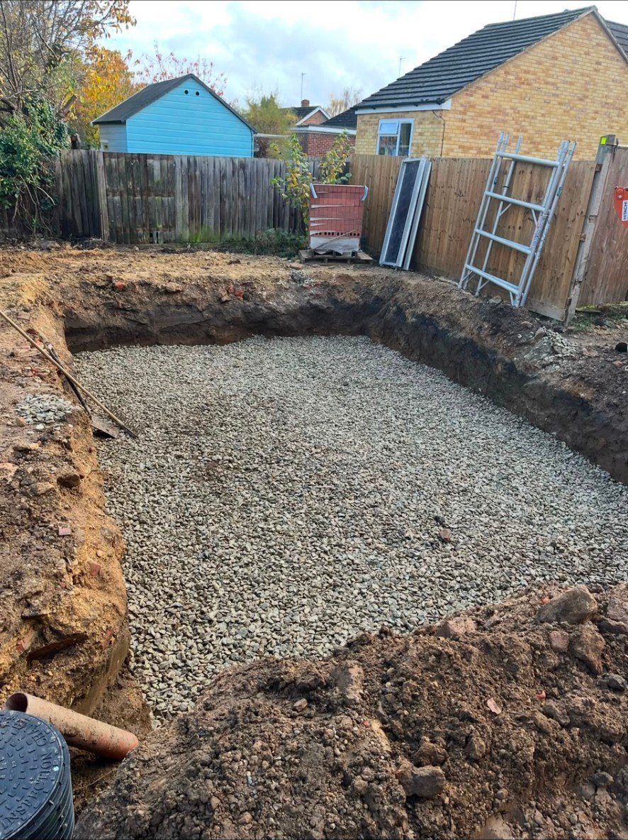 Garden excavation showing Type 1 MOT sub-base laid in a deep excavated trench for a patio base.