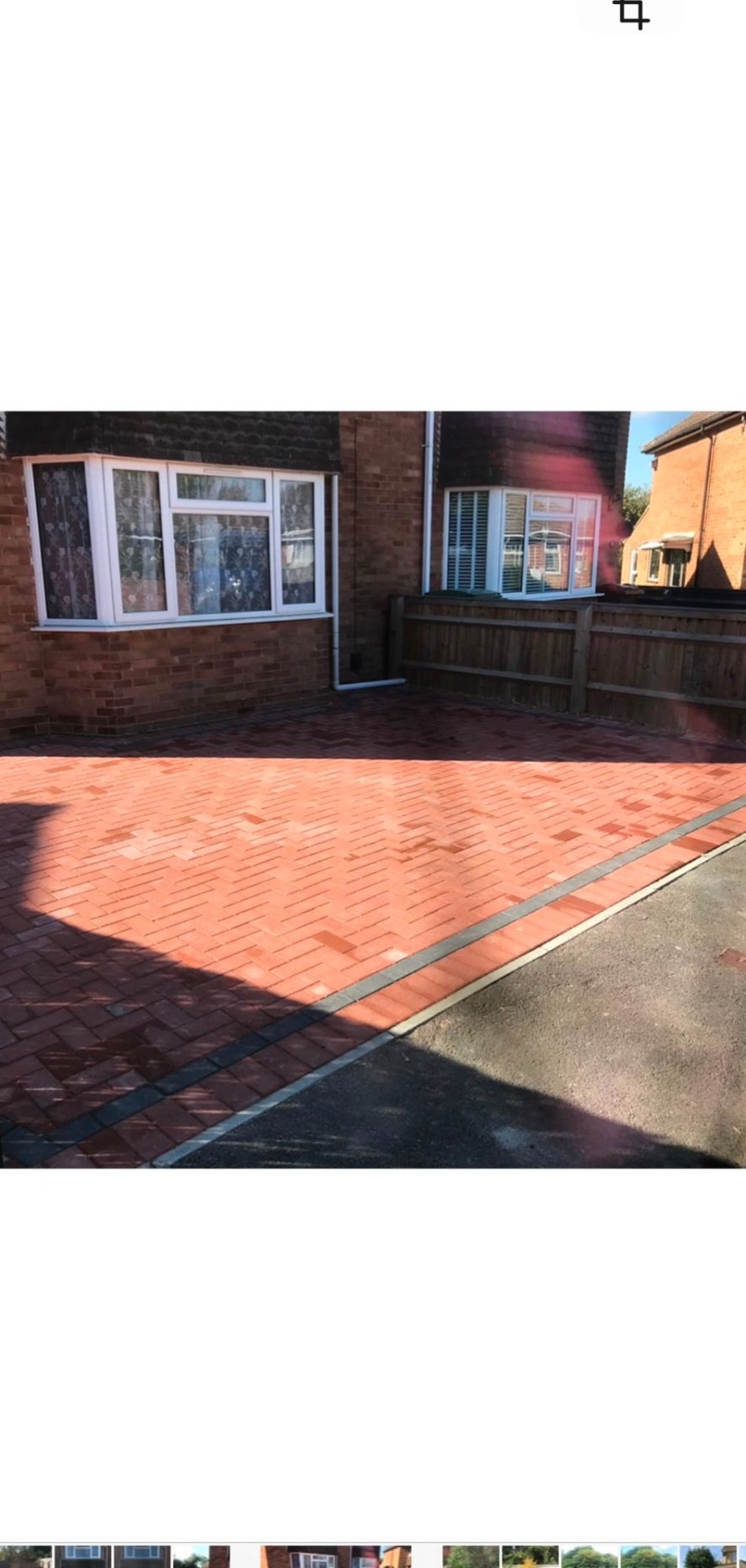 Red herringbone block paving driveway with charcoal border next to a brick house