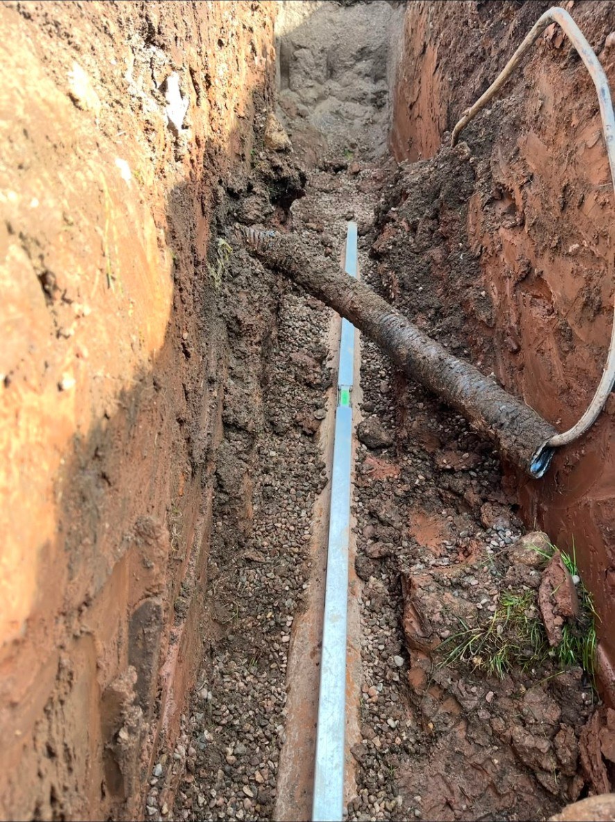 Groundworks footing excavation with a spirit level checking depth and base levels in a trench.